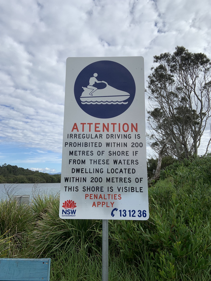 Sign reads ATTENTION IRREGULAR DRIVING IS PROHIBITED WITHIN 200 METRES OF SHORE IF FROM THESE WATERS DWELLING LOCATED WITHIN 200 METRES OF THIS SHORE IS VISIBLE PENALTIES APPLY