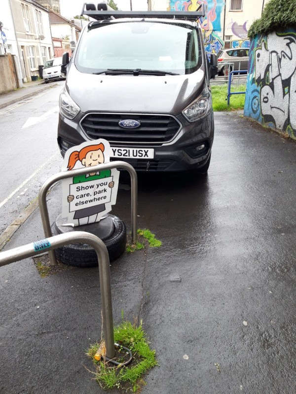 Van parked on pavement in front of sign reading Show you care, park elsewhere