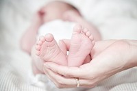 Baby's feet being held by female hand. Image courtesy of Wikimedia Commons.
